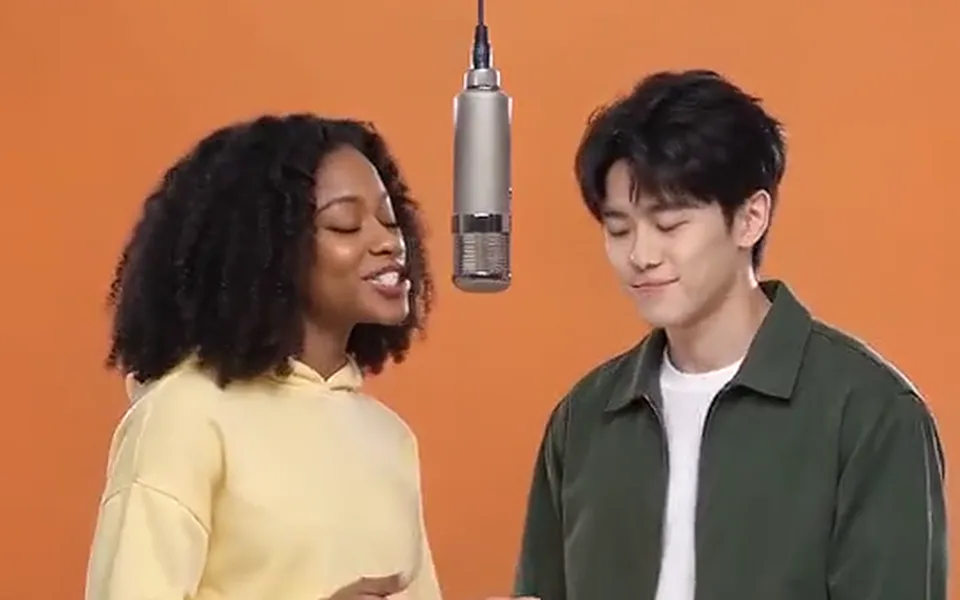 Frame from our demo: two friends in the orange booth under the hanging mic.